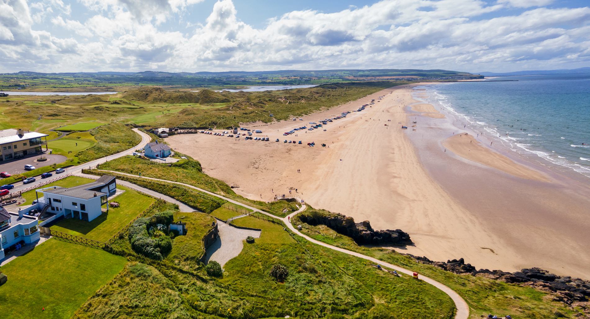 Wide sandy beach backed by grassy dunes and a golf course at Strand Head, County Londonderry.