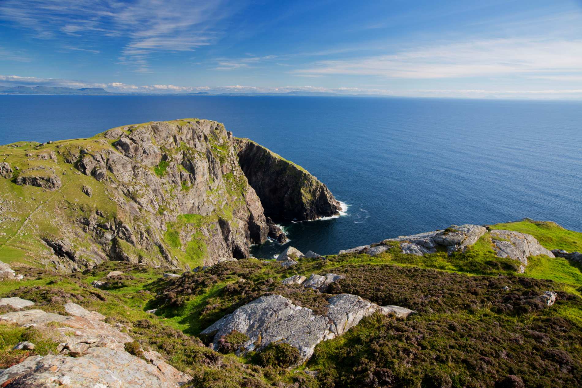 A rocky cliff juts into the Atlantic beneath a clear blue sky in this summer showcase of Ireland’s coastline.