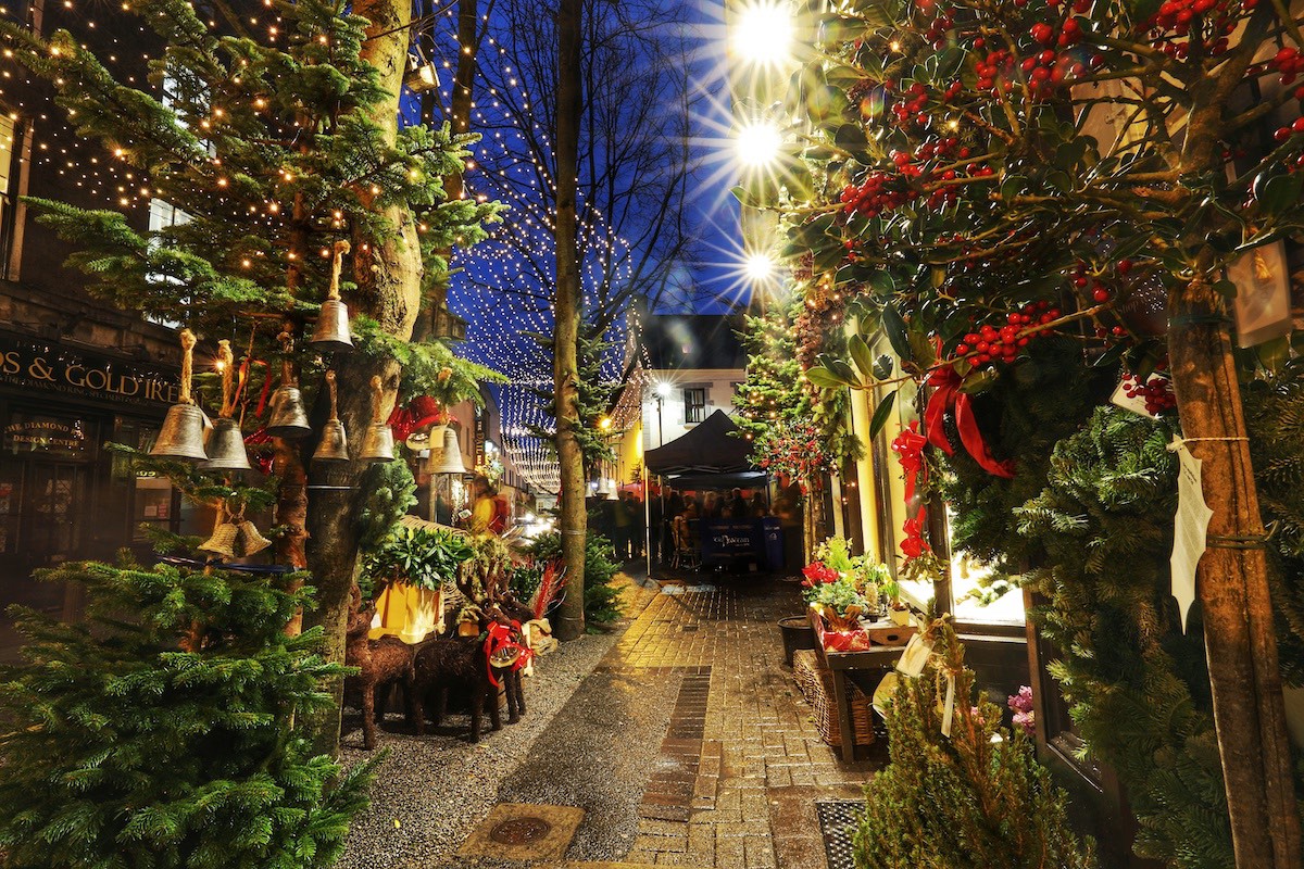Festive alley in Galway decorated with Christmas wreaths, lights, and market stalls.