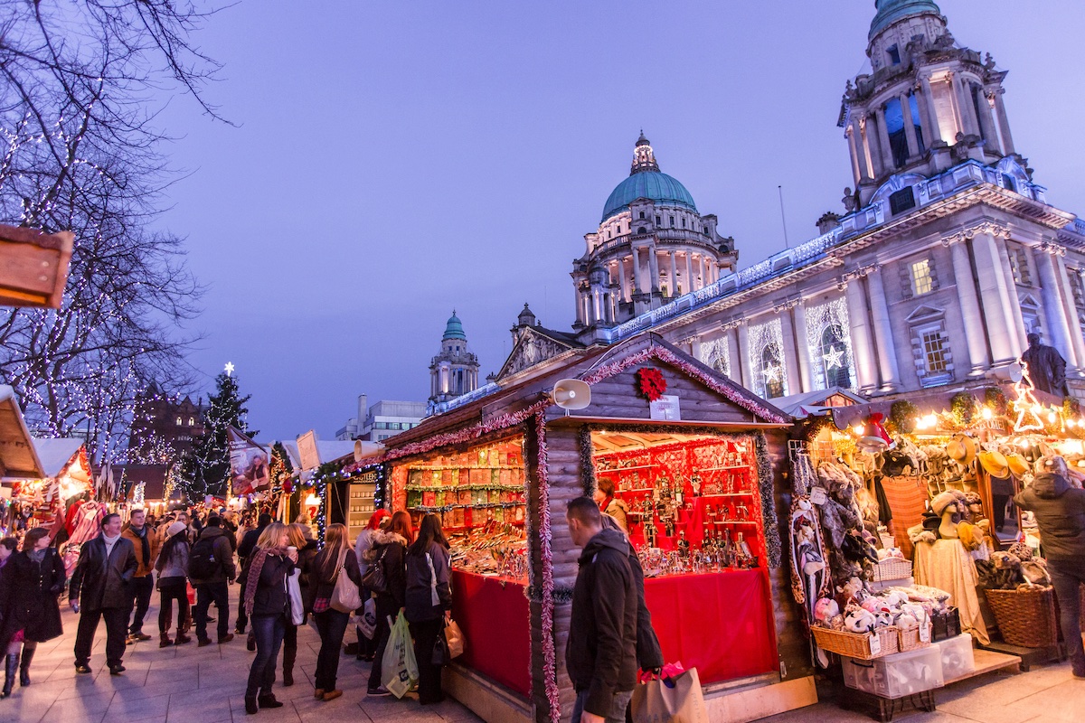Christmas market stalls outside Belfast City Hall with festive lights and decorations.
