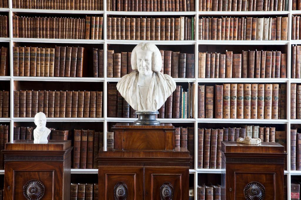 Bust of a judge in white marble displayed in front of antique bookshelves inside Armagh Robinson Library.