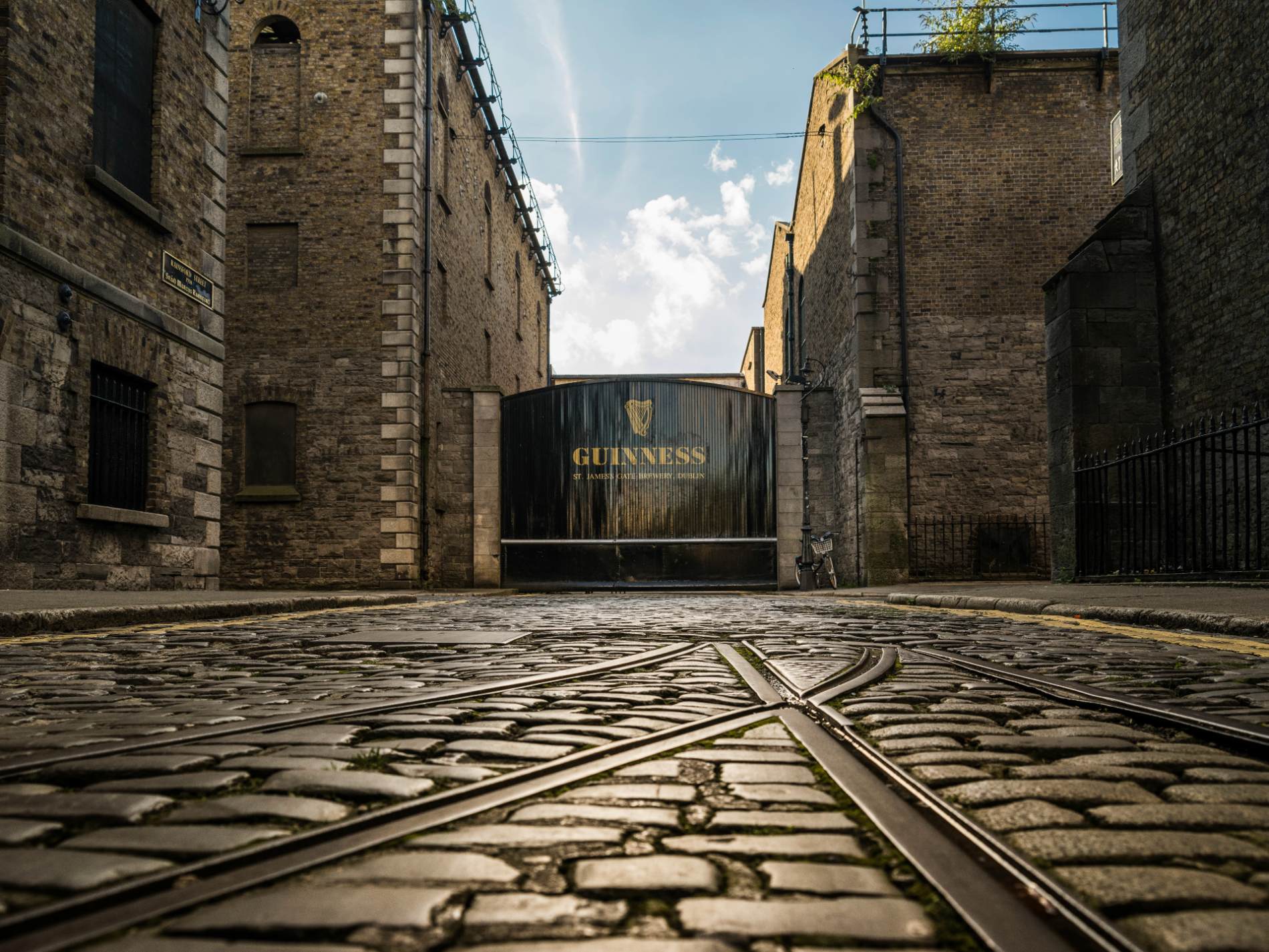 The black Guinness gates at St James’s Gate Brewery in Dublin with cobblestones in the foreground.