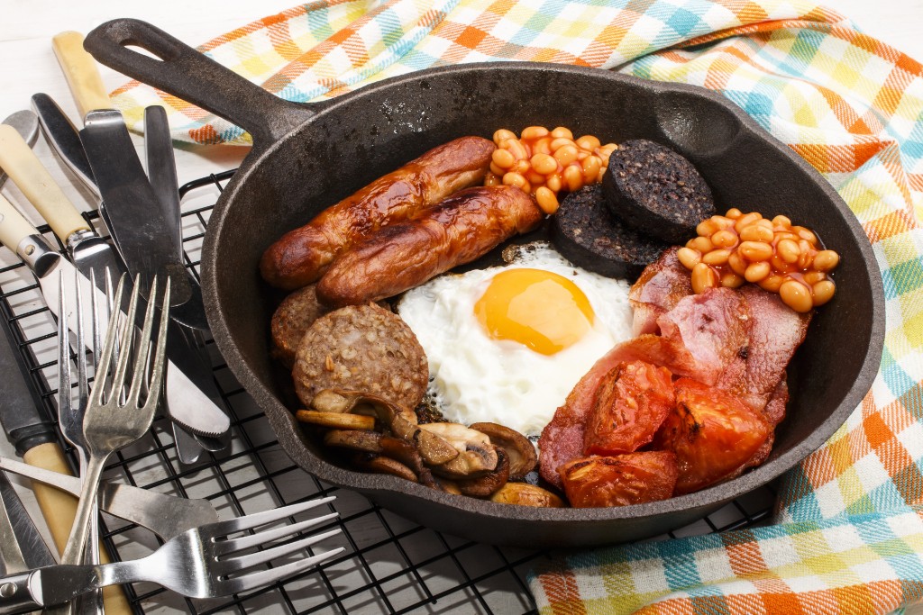 Traditional full Irish breakfast in a cast-iron pan with sausages, egg, and bacon.