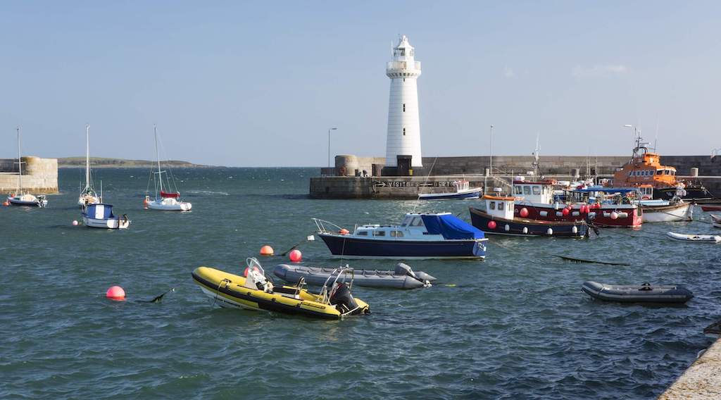 Donaghadee Lighthouse stands above a harbour with fishing boats and yachts in County Down.