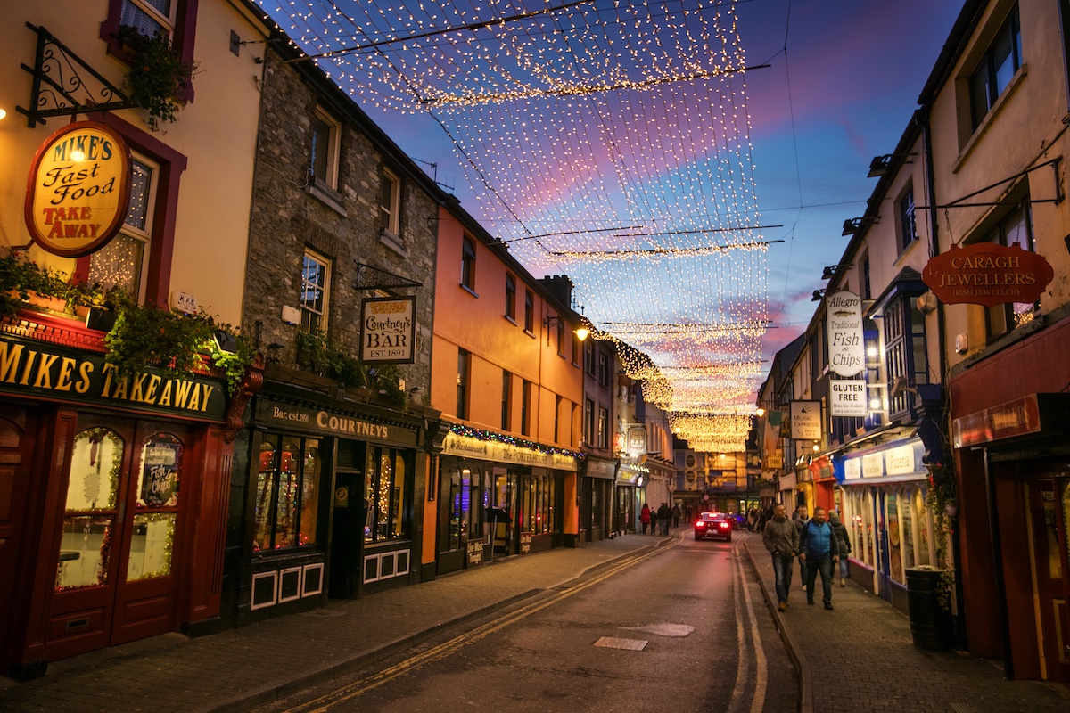 Street in Killarney decorated with Christmas lights and lined with pubs and shops.