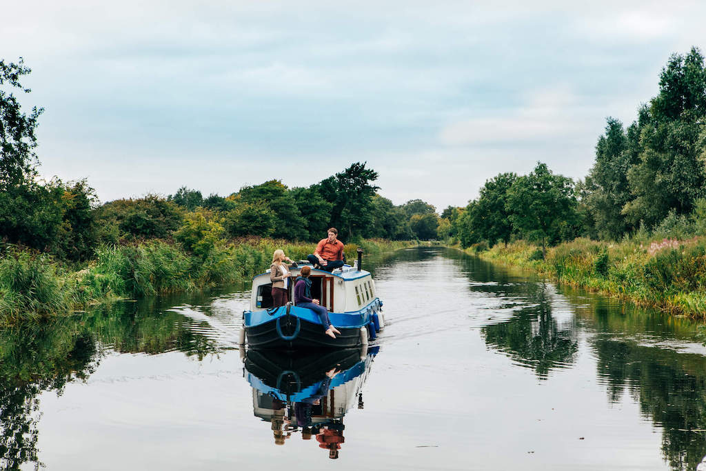 Family standing on a barge cruising through the Grand Canal near Sallins, County Kildare.
