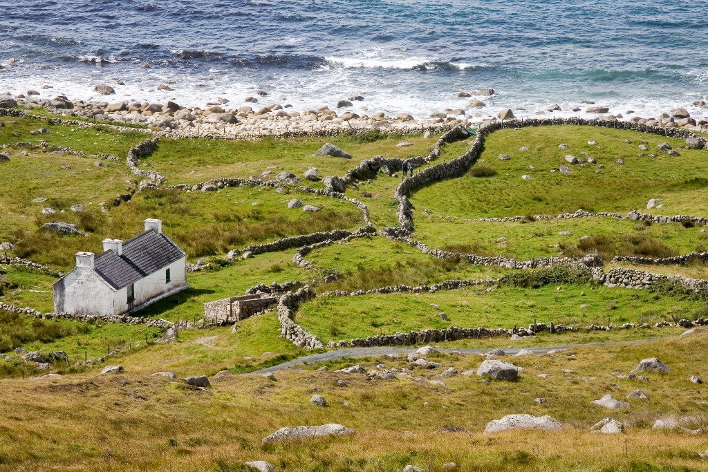 White cottage with stone walls and patchwork fields by the Atlantic at Bloody Foreland, County Donegal.