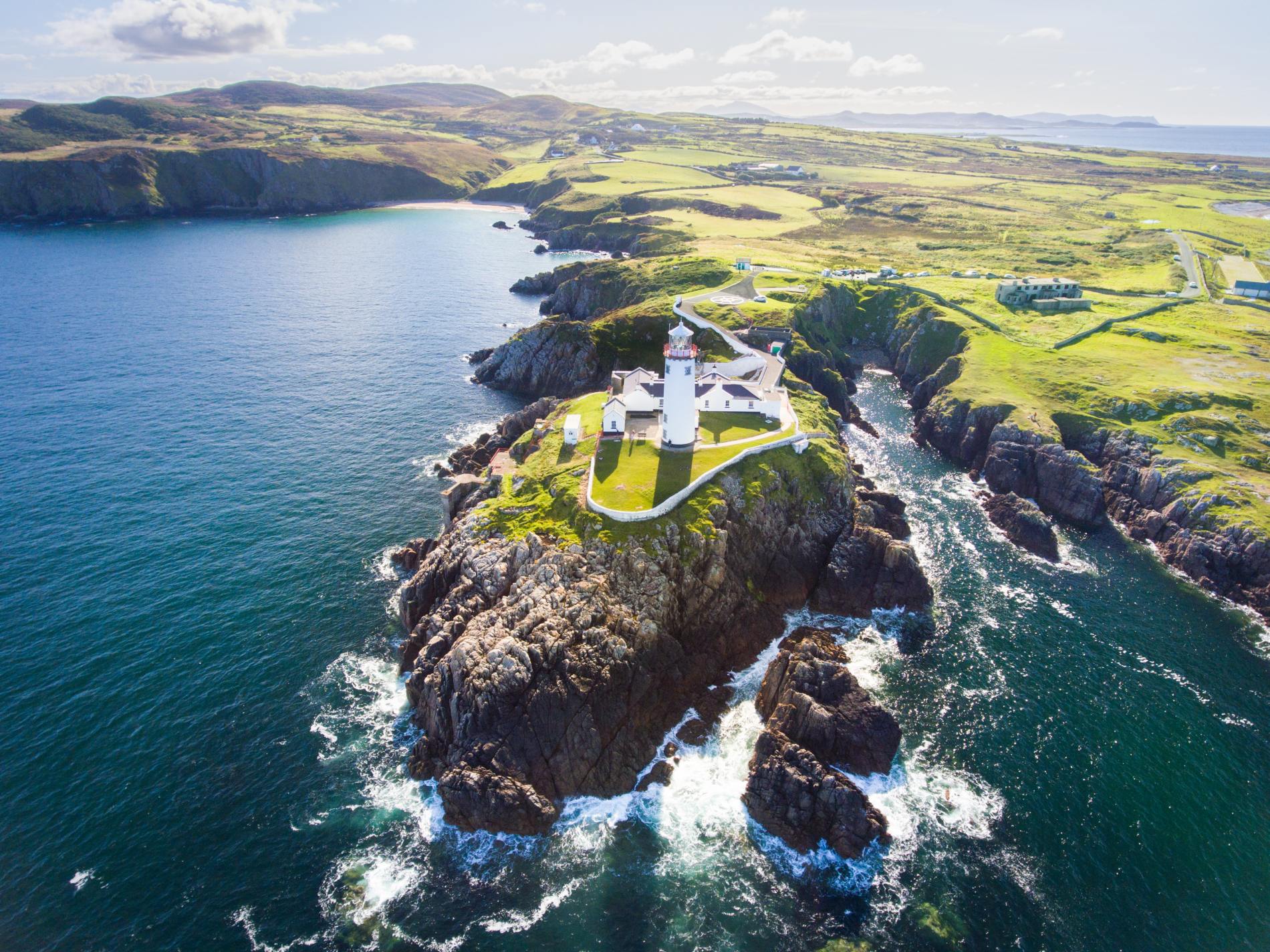 Fanad Head Lighthouse on rocky peninsula surrounded by Atlantic Ocean in County Donegal.