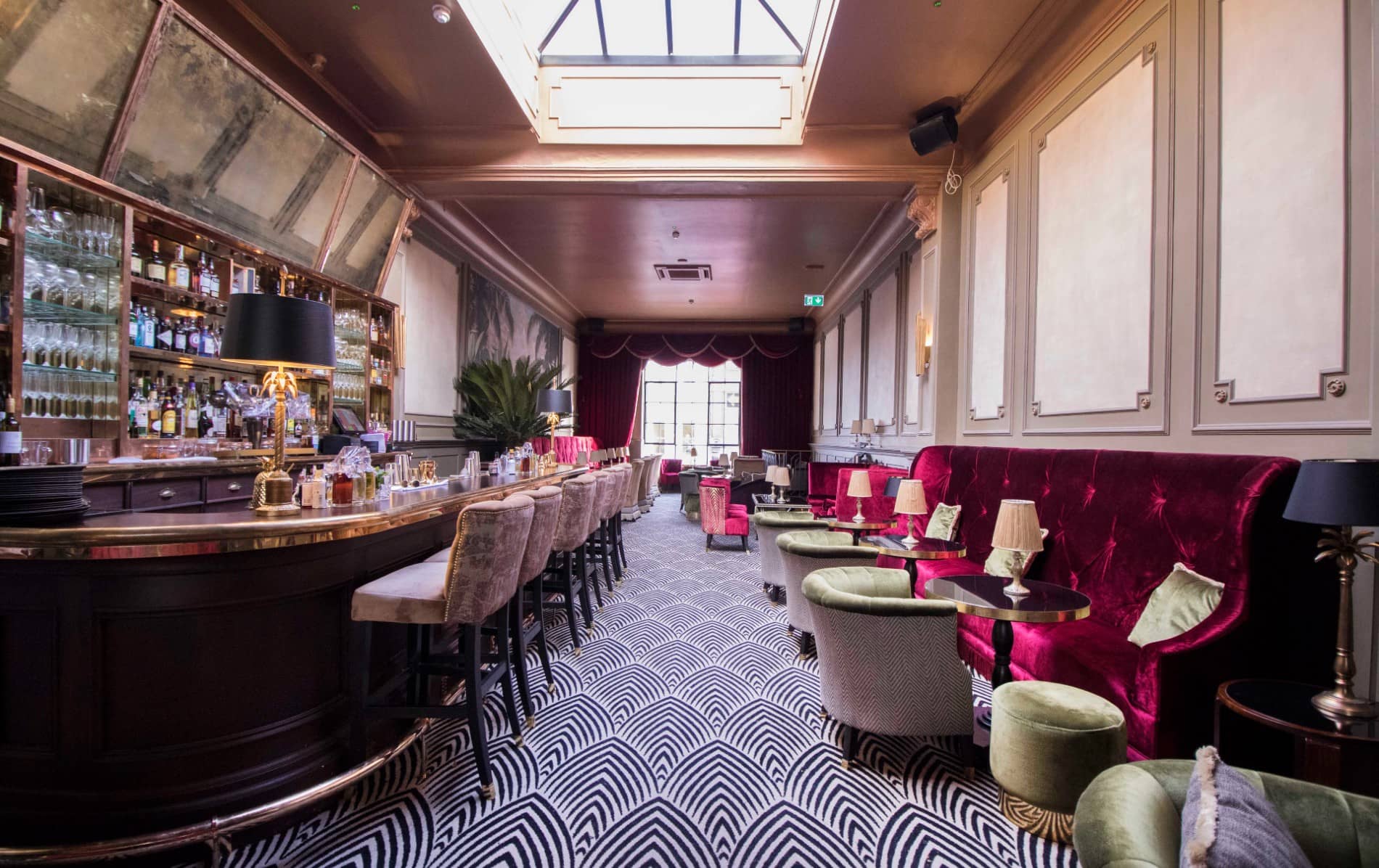 Elegant cocktail bar with velvet seating, patterned carpet and a mirrored backlit counter at the Stella Cinema.