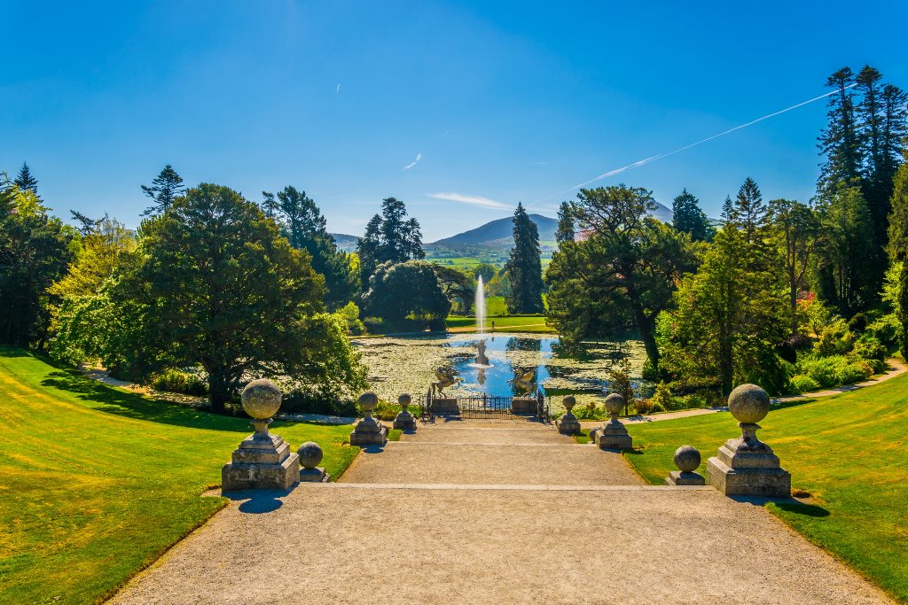 Stone steps lead to a pond with fountain and mountain views at Powerscourt.