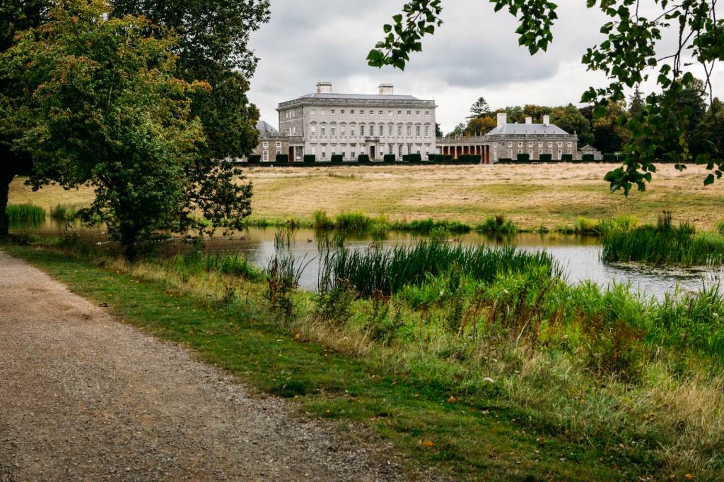 View across a pond to Castletown House, a grand Palladian mansion framed by trees and open fields in Kildare.