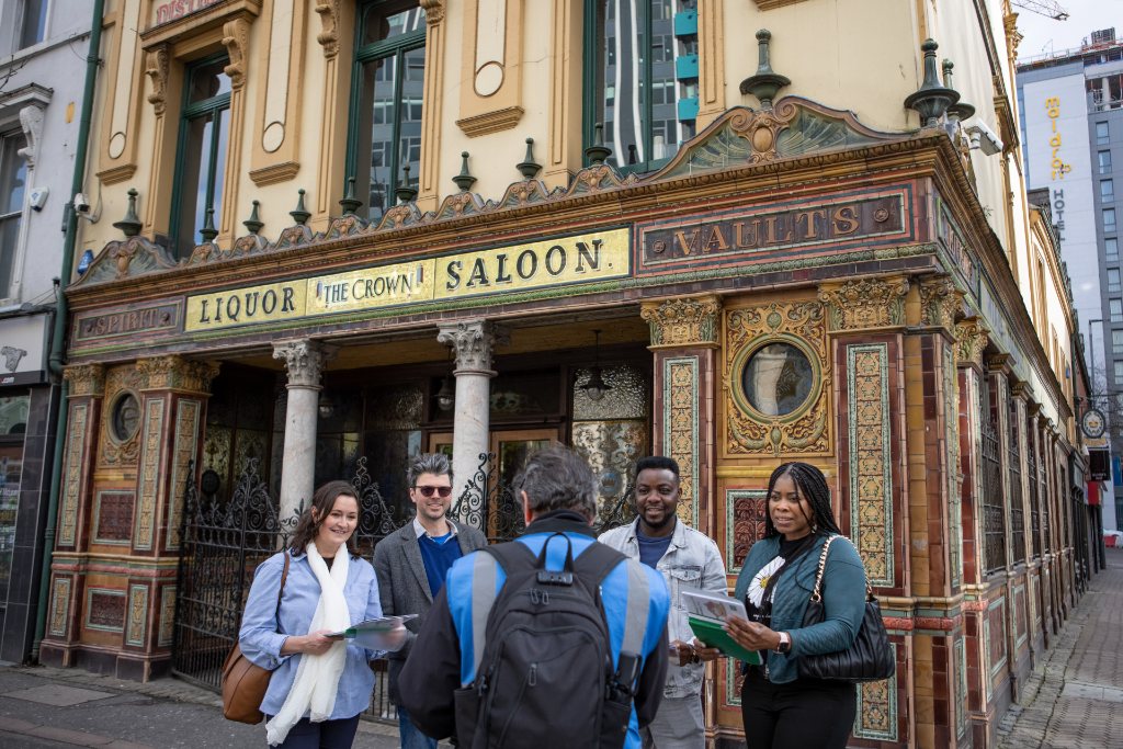 Group of people outside the ornate Victorian façade of the Crown Liquor Saloon in Belfast.