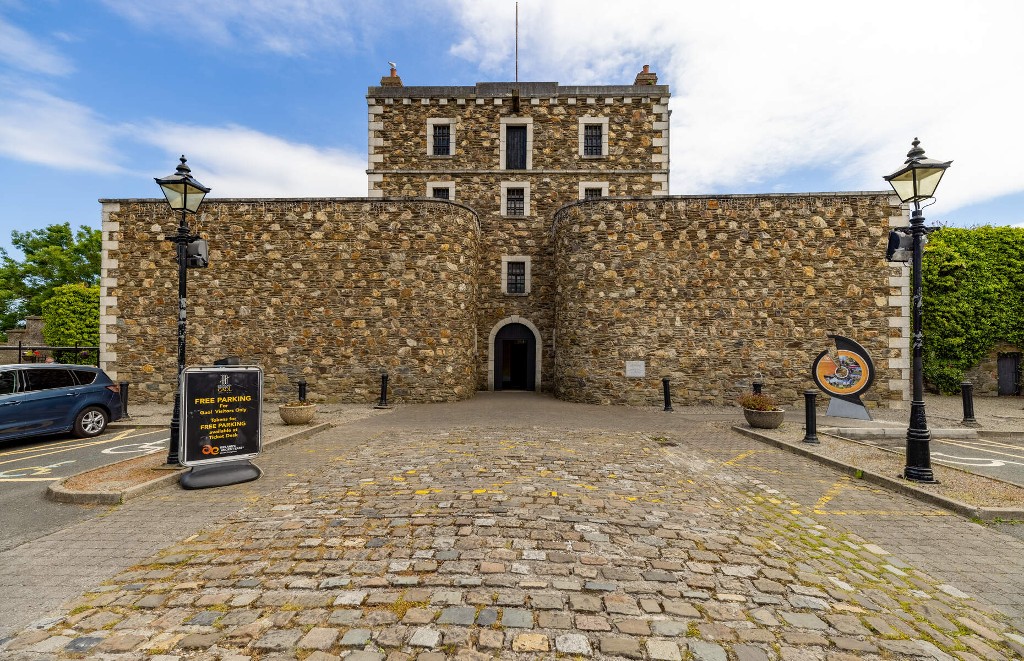 Stone facade of Wicklow Gaol in County Wicklow, framed by vintage lampposts and cobblestone courtyard.