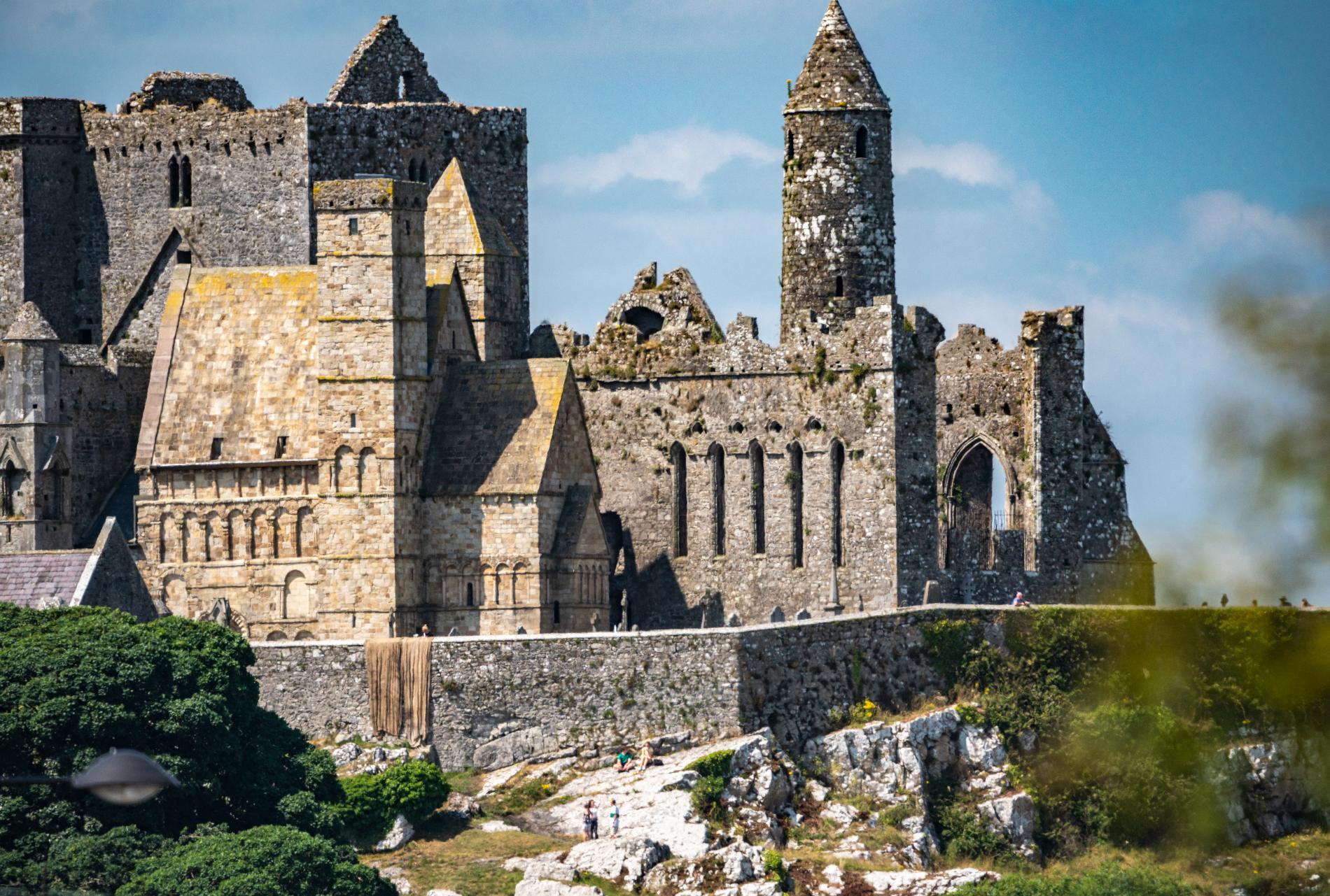 Close-up of Cormac’s Chapel and medieval ruins at the Rock of Cashel under a clear blue sky.