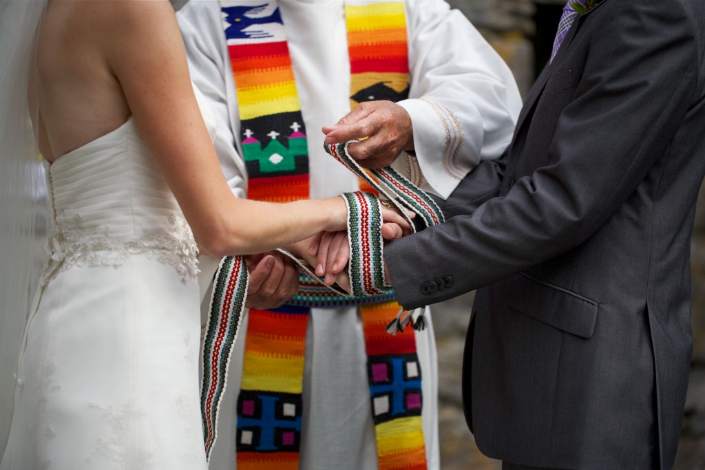 Close-up of handfasting ritual with multicoloured crios binding a couple’s hands during a traditional Irish wedding ceremony.