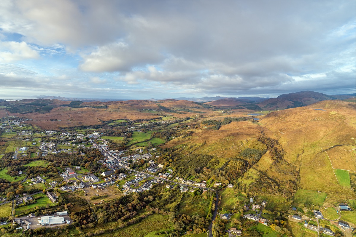 Aerial view over Glenties village surrounded by rolling hills and patchwork fields in County Donegal.