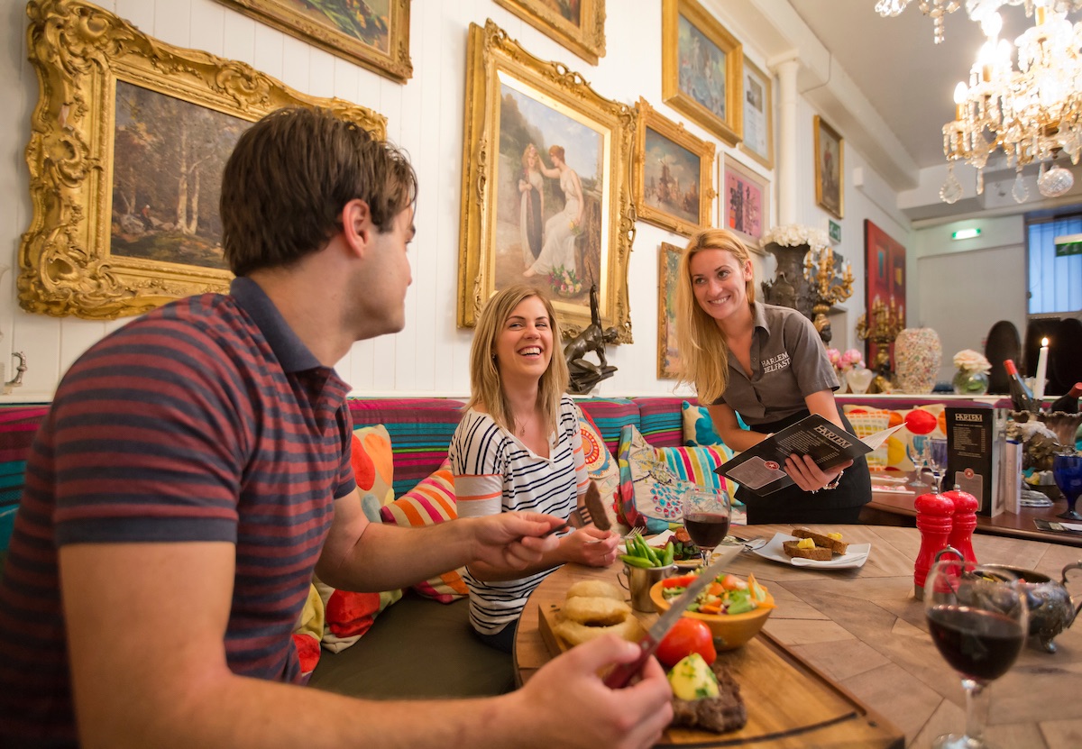 Couple enjoying dinner and wine at the colourful Belfast restaurant, Harlem, with smiling waitress.