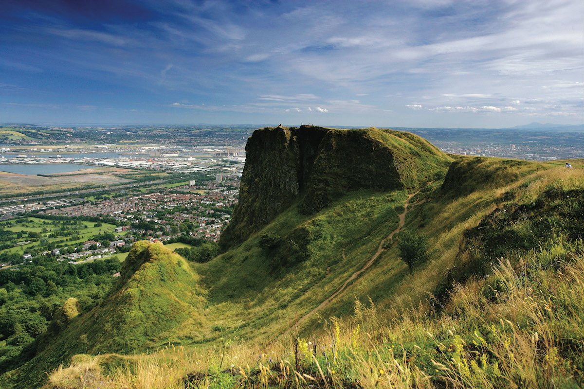 View from Cave Hill in Belfast with grassy cliffs overlooking the city and coastline.