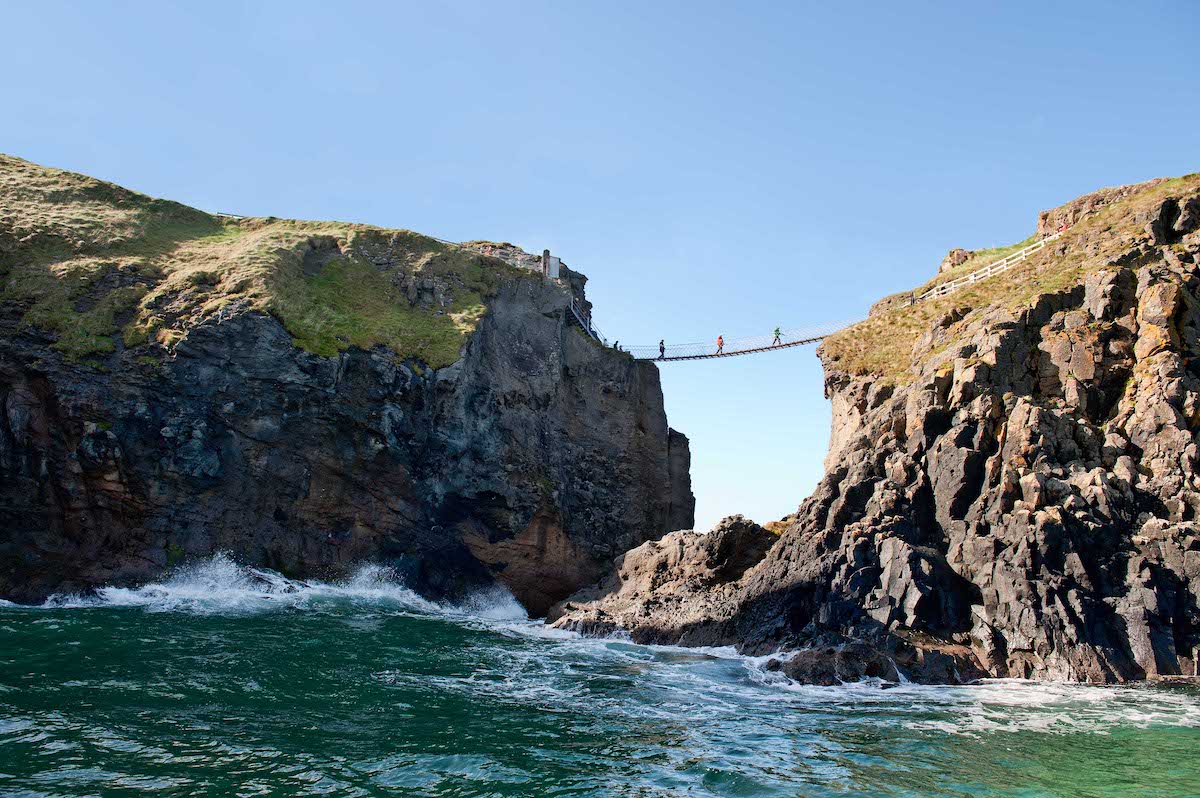 Visitors crossing Carrick-a-Rede Rope Bridge over cliffs and sea near Belfast.