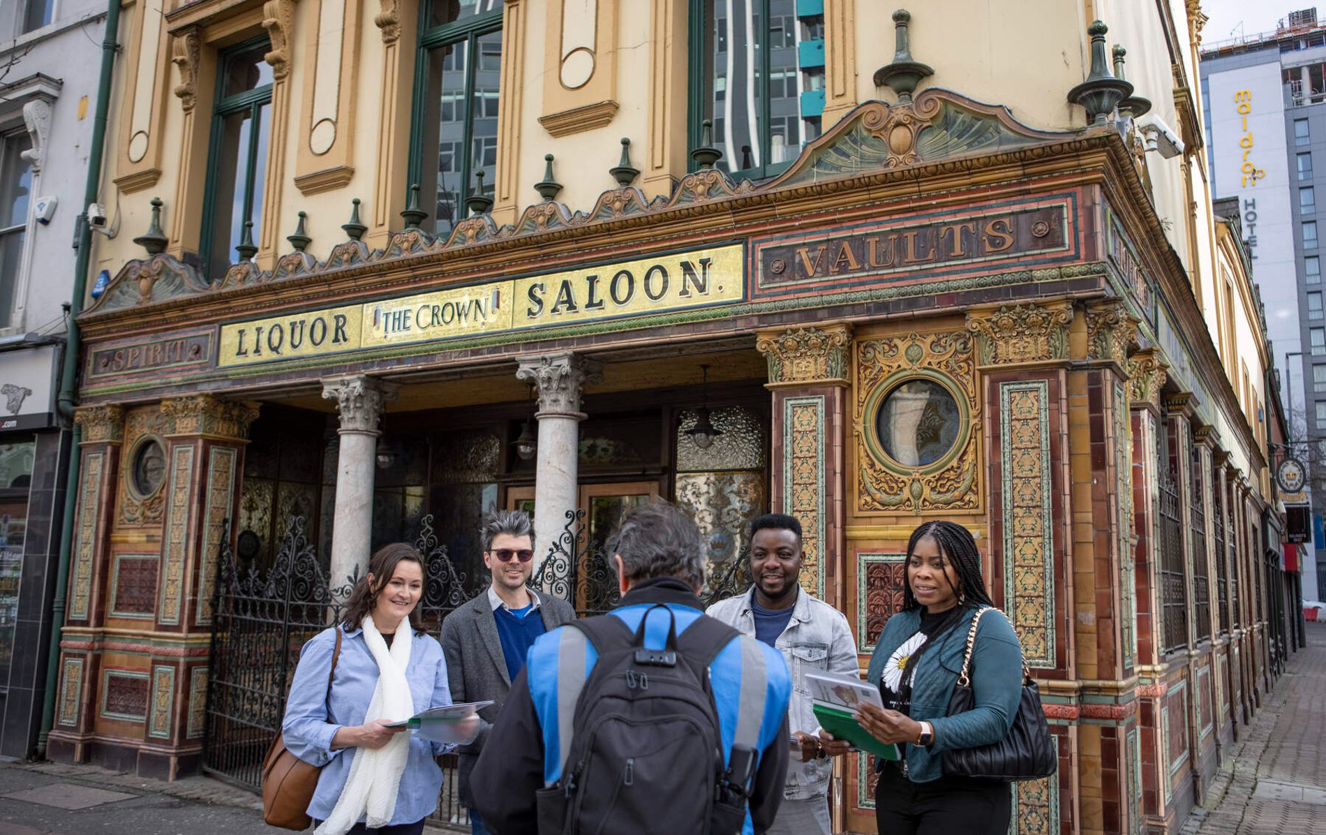 Tour group stands outside the Crown Liquor Saloon’s ornate Victorian tiled facade in Belfast city centre.
