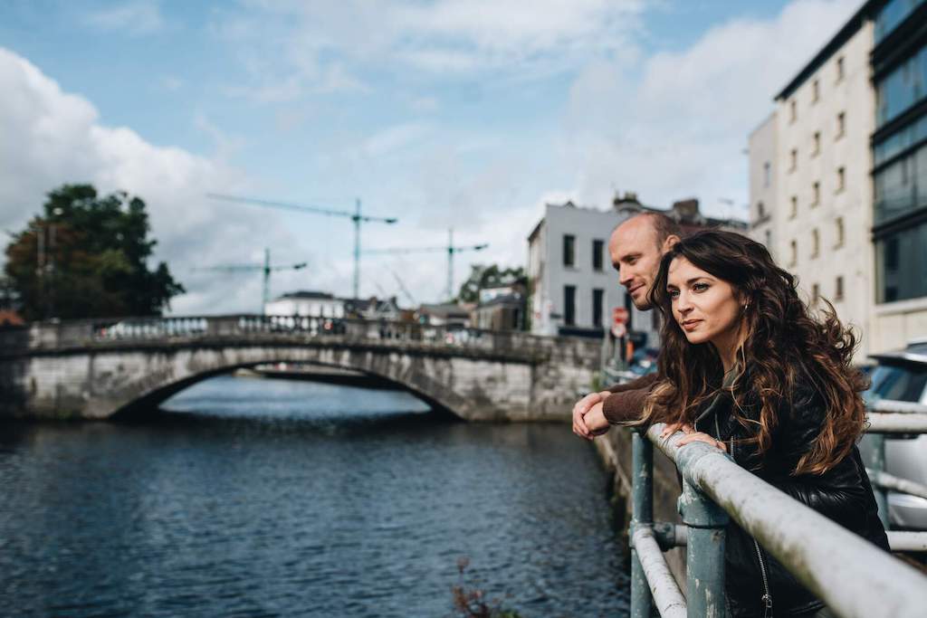 A couple leaning on a railing overlooking a bridge on the River Lee in Cork.