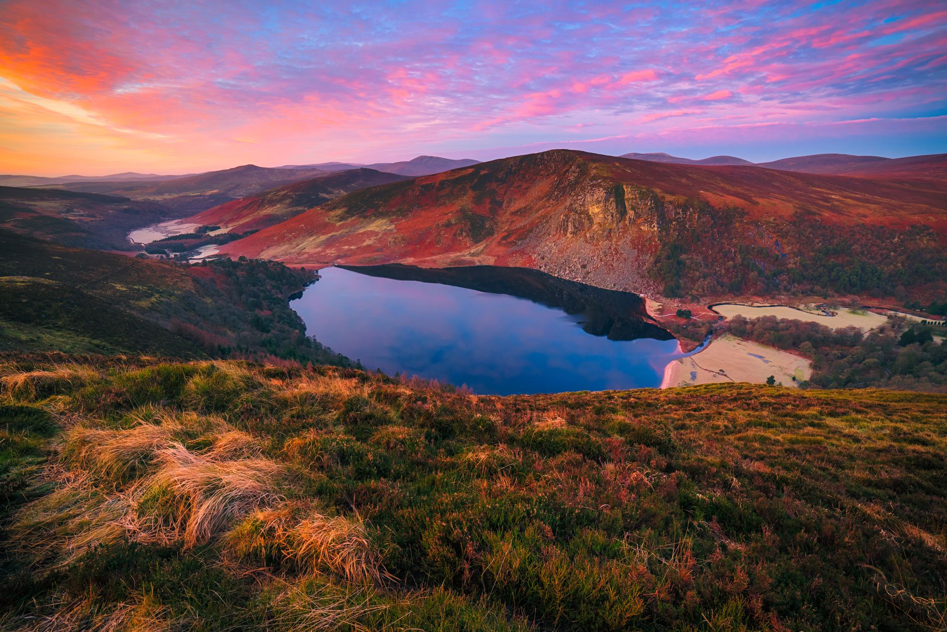 Lough Tay in the Wicklow Mountains at sunset, with vibrant pink and orange skies.
