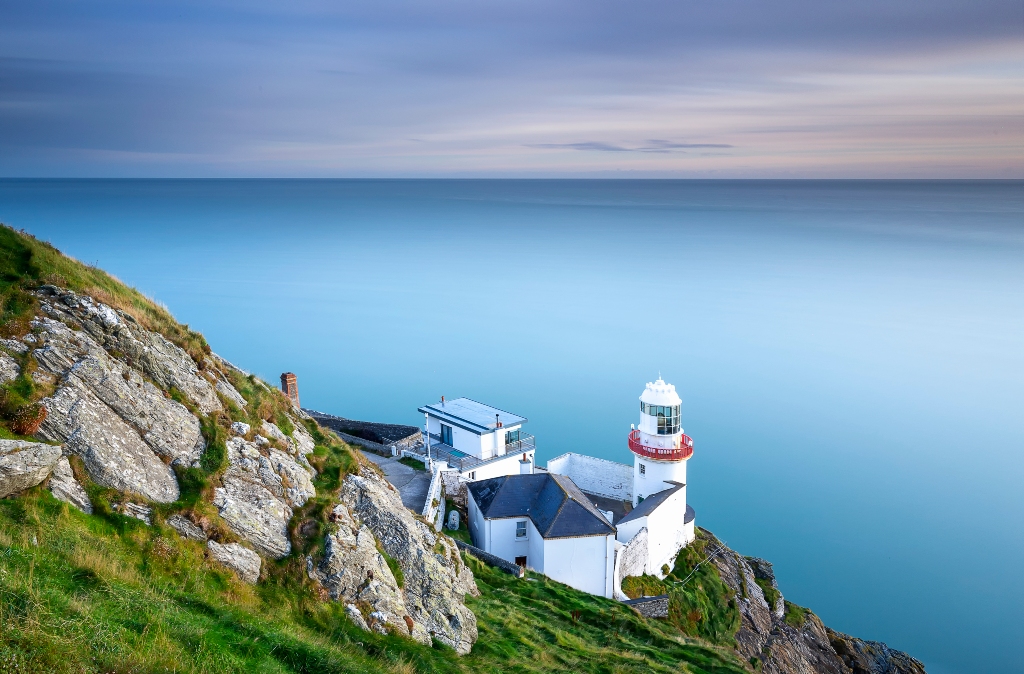 Wicklow Lighthouse perched on the cliffs of County Wicklow overlooking the calm Irish Sea.