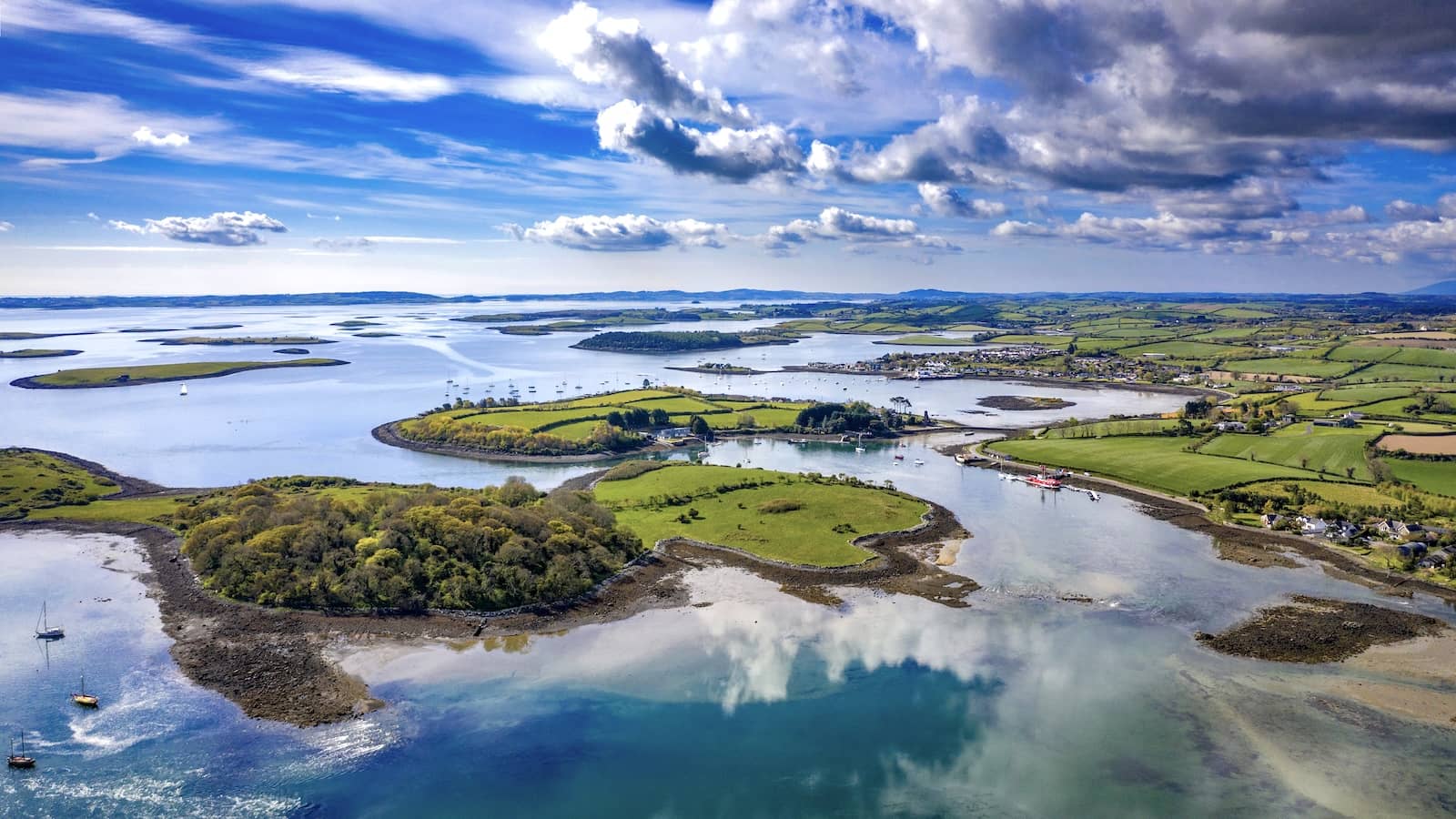 Aerial view of Strangford Lough in County Down with winding waterways, green farmland and dramatic clouds.