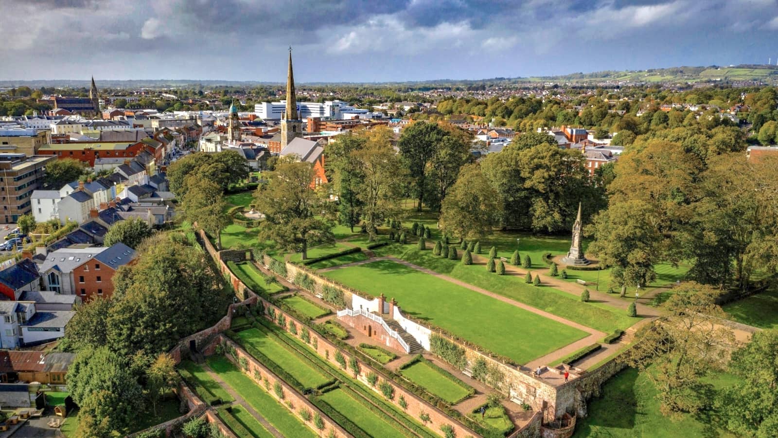 View over Lisburn city with Castle Gardens, historic churches and surrounding countryside under dramatic skies.