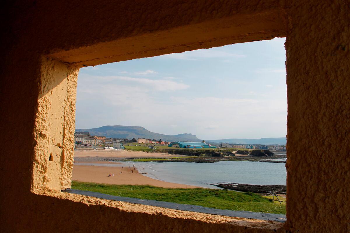 Looking out at Bundoran Beach in County Donegal from a concrete window on a sunny, blue-sky day.