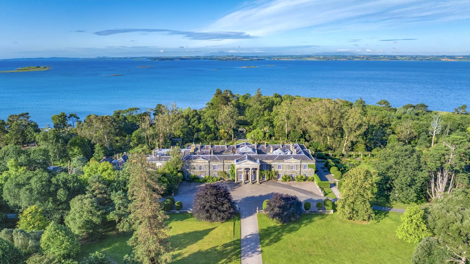 Aerial view of Mount Stewart estate in County Down surrounded by woodland and overlooking Strangford Lough on a sunny day.