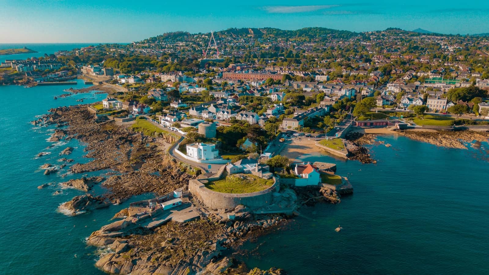 Aerial view of Sandycove’s rocky coastline and Martello tower with Dublin Bay in the background.