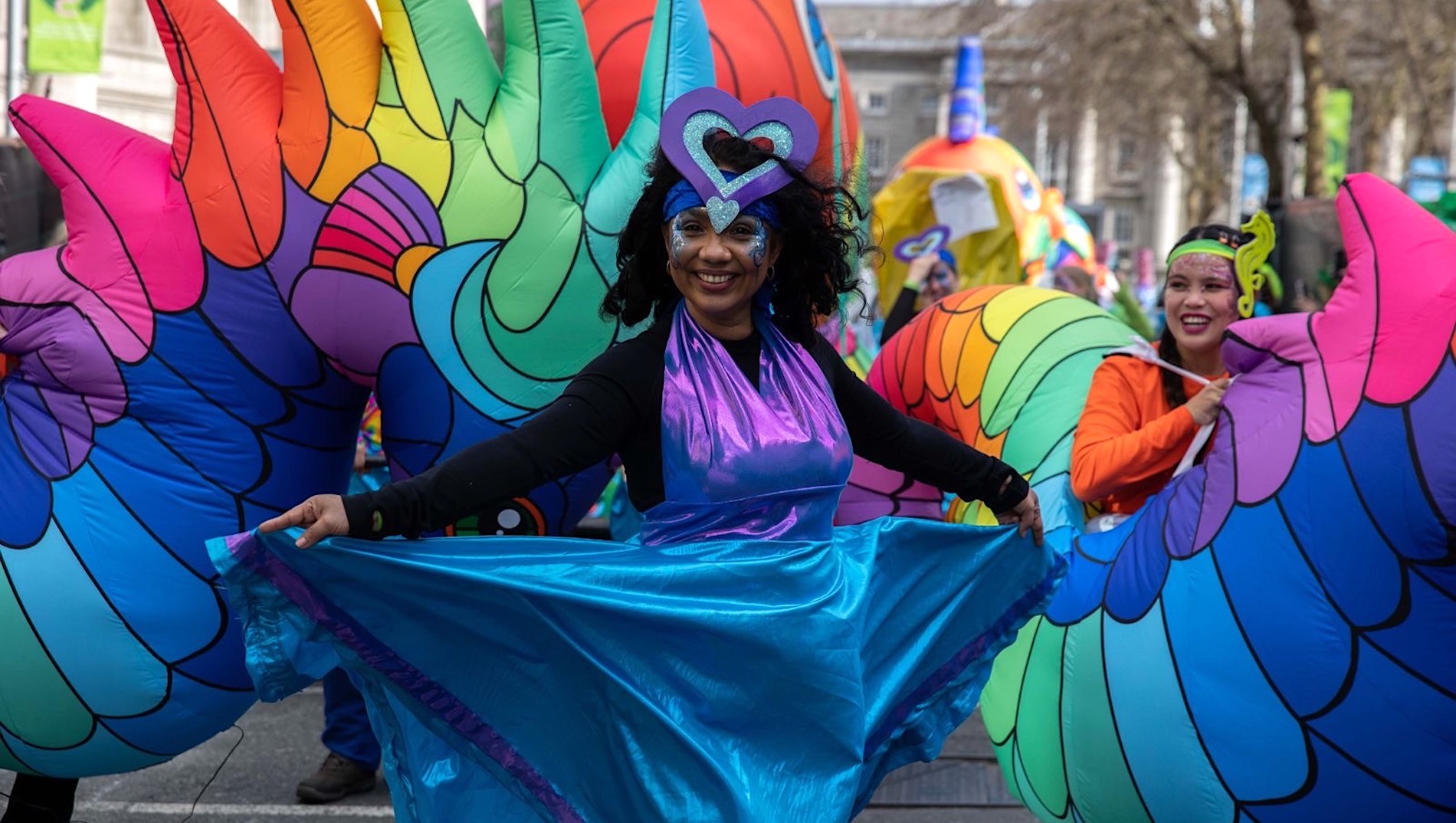 Performer in colourful costume smiling during Dublin's St Patrick's Day parade.