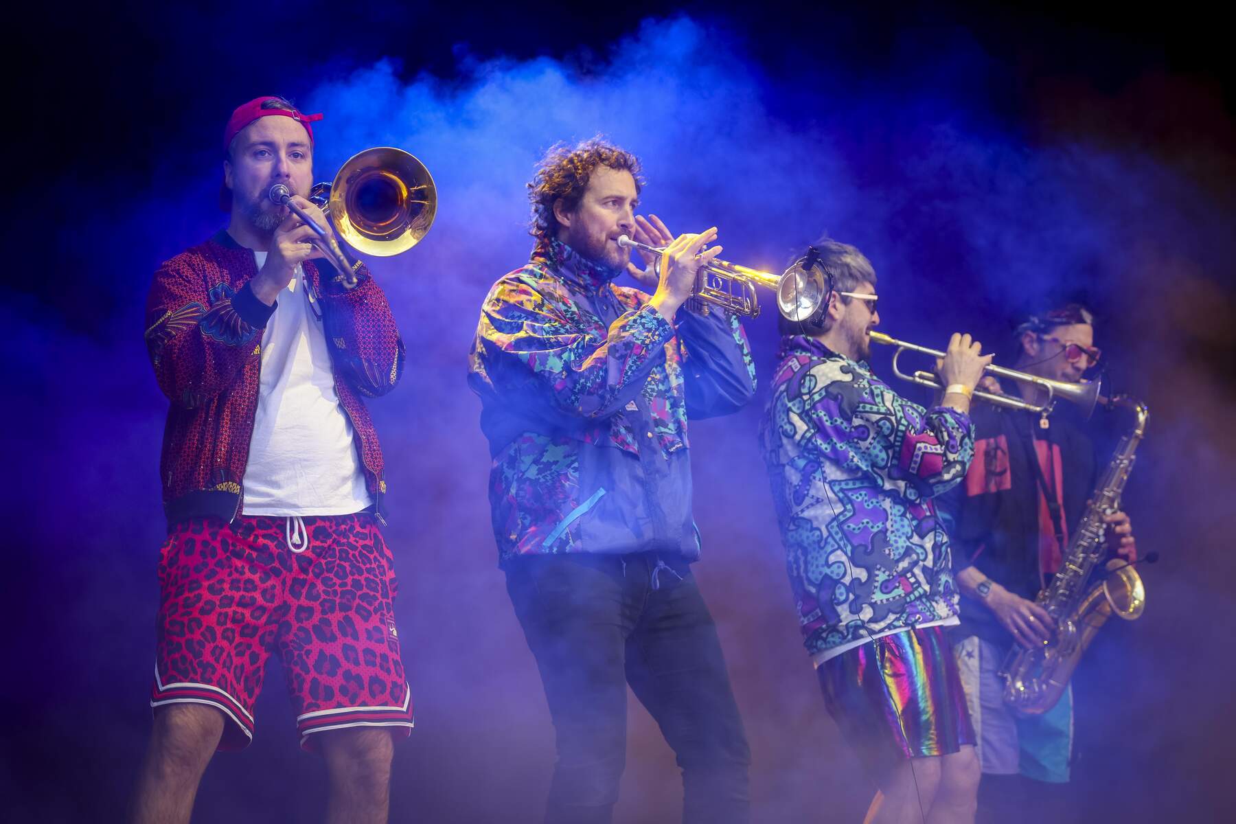 A brass band in colourful outfits during a live performance in Dublin, with energy and movement in the scene.