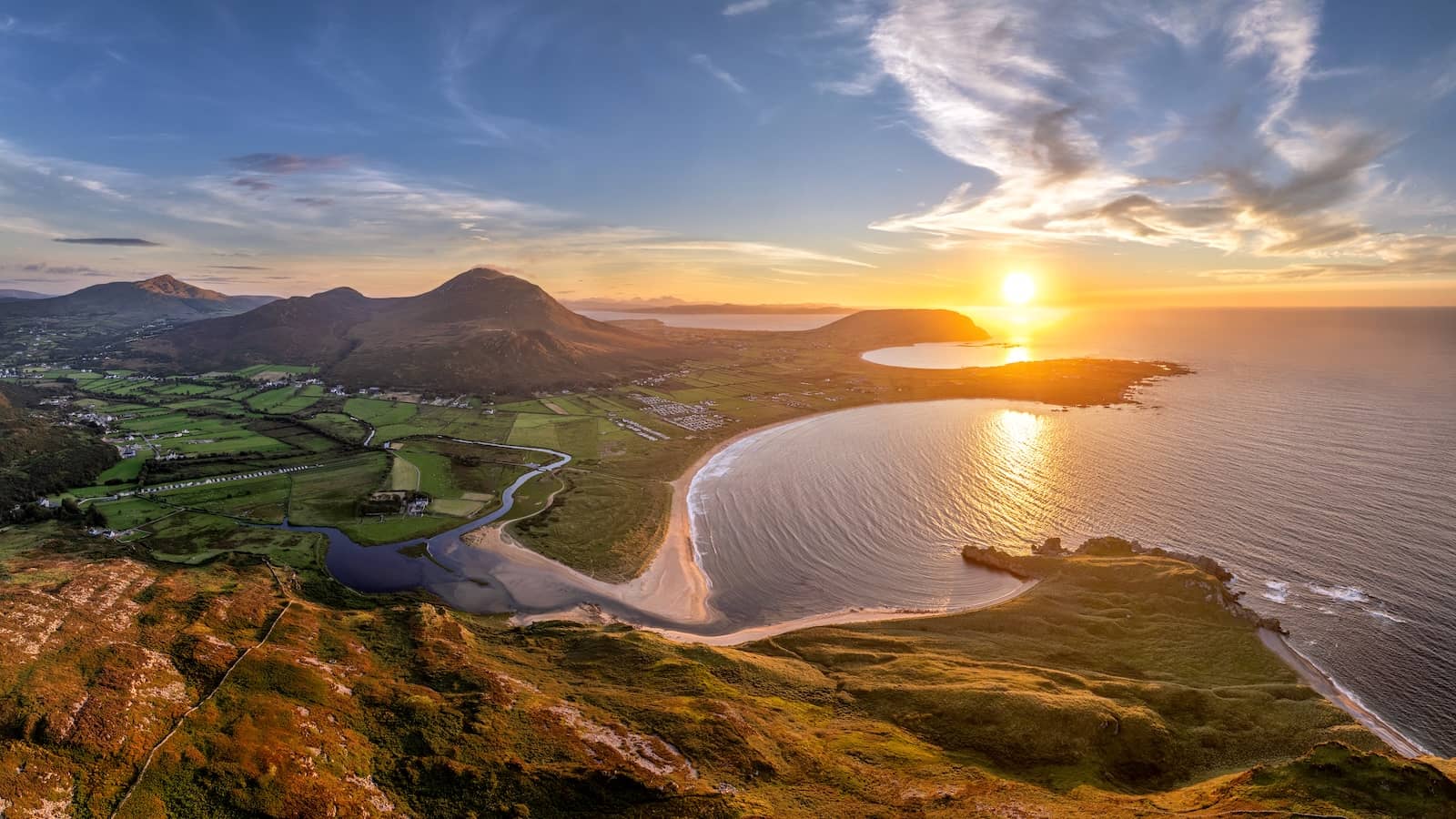 Panoramic sunset over Tullagh Bay with rolling hills, beaches, and farmland on the Inishowen Peninsula, County Donegal.