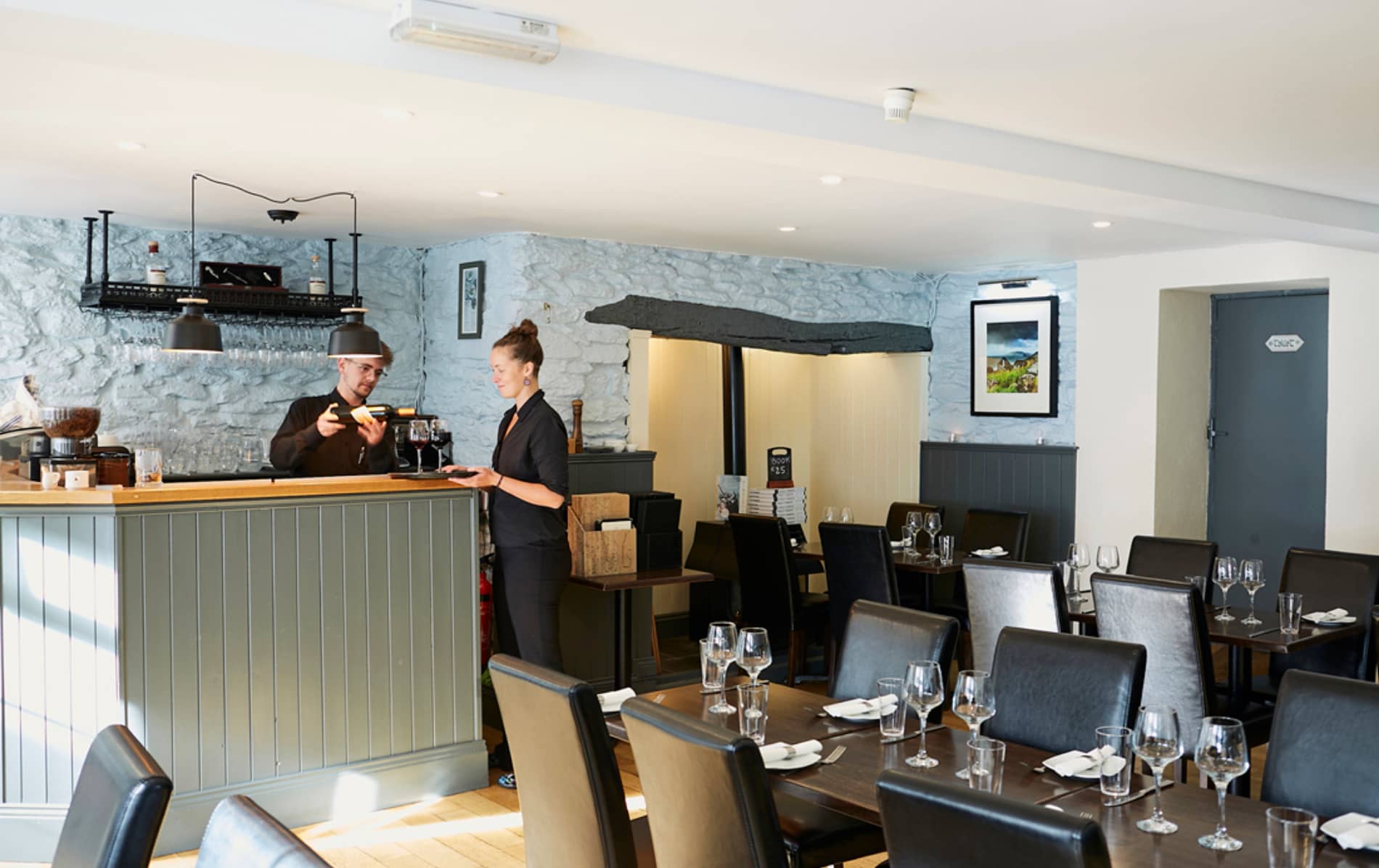 Staff serve wine inside Land to Sea restaurant in Dingle, County Kerry, with set dining tables.