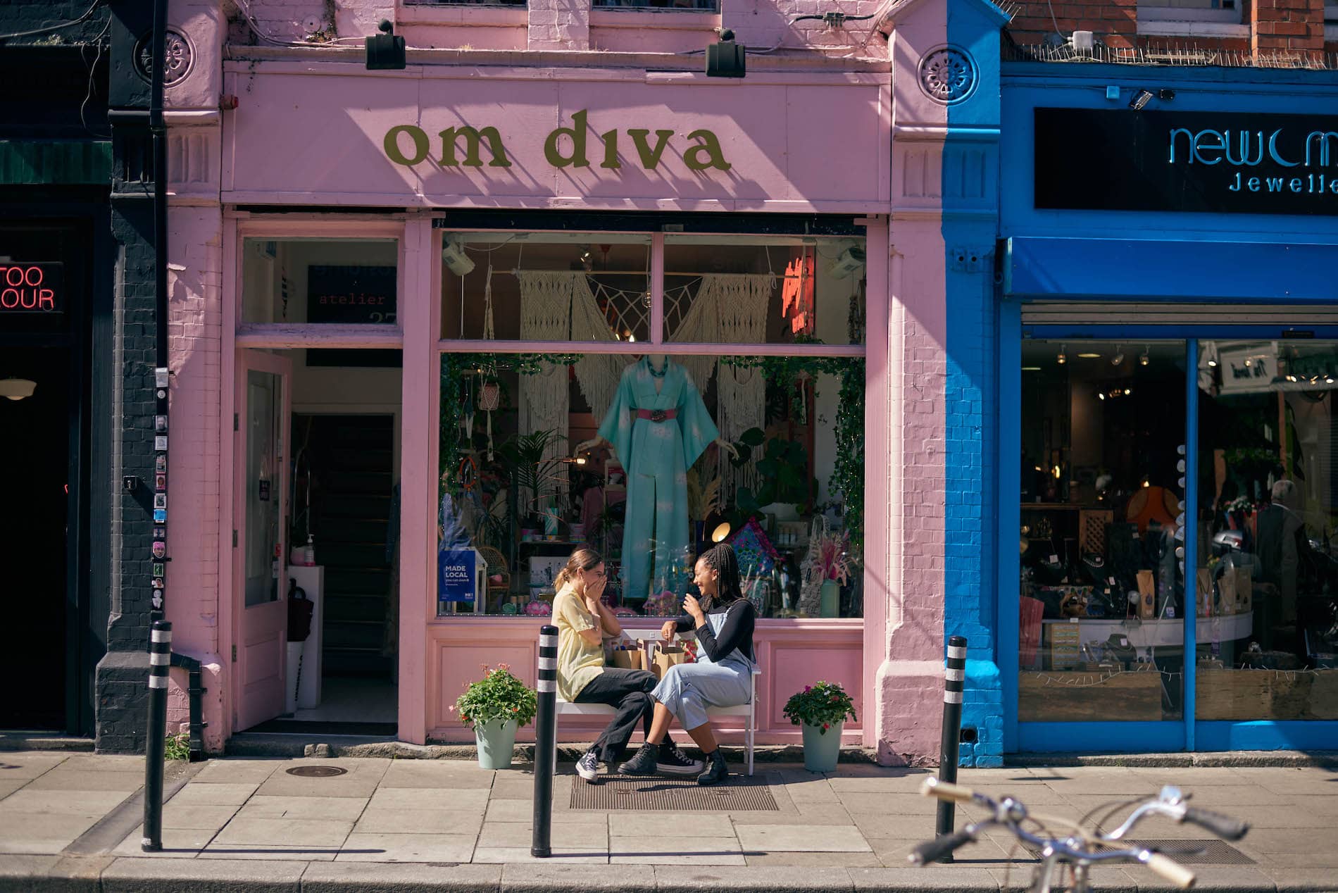 Two people chat outside Dublin’s Om Diva boutique, known for vibrant fashion and traditional Irish craft.