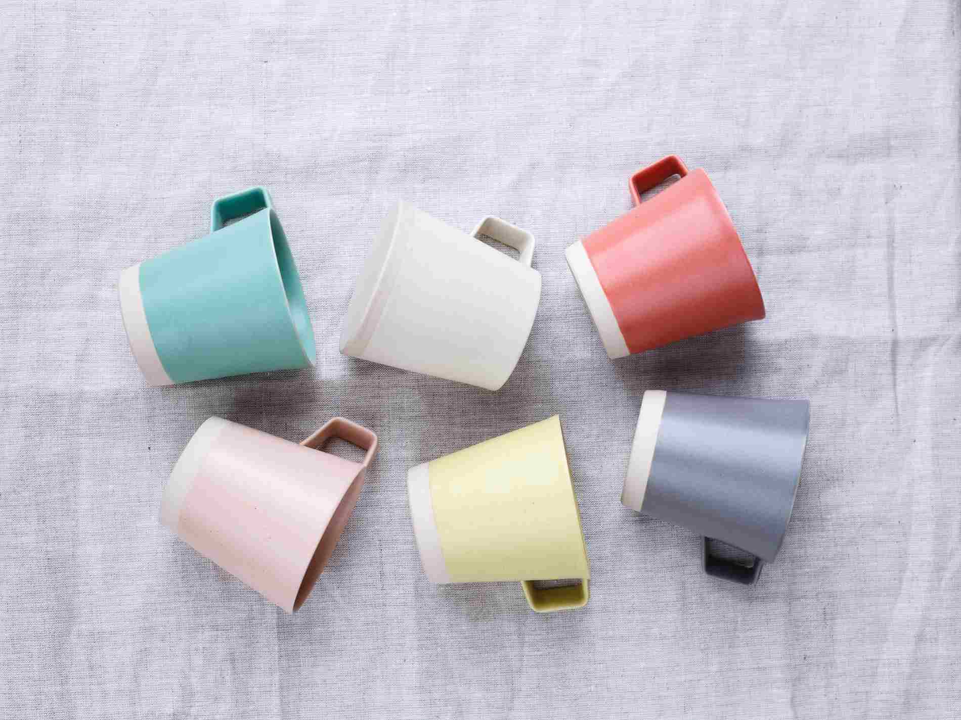 Set of pastel-toned mugs arranged in a circular pattern on linen, handmade by Arran Street East in Dublin.