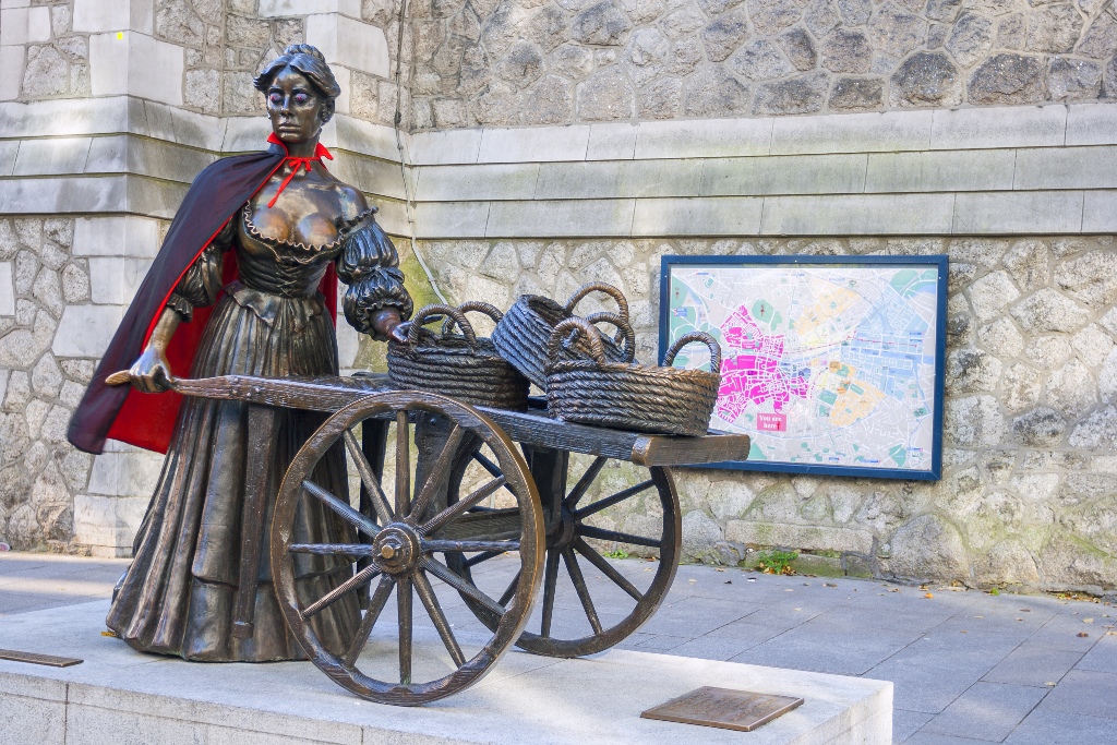 Molly Malone statue wearing a Halloween cape with a cart of baskets in Dublin city centre.