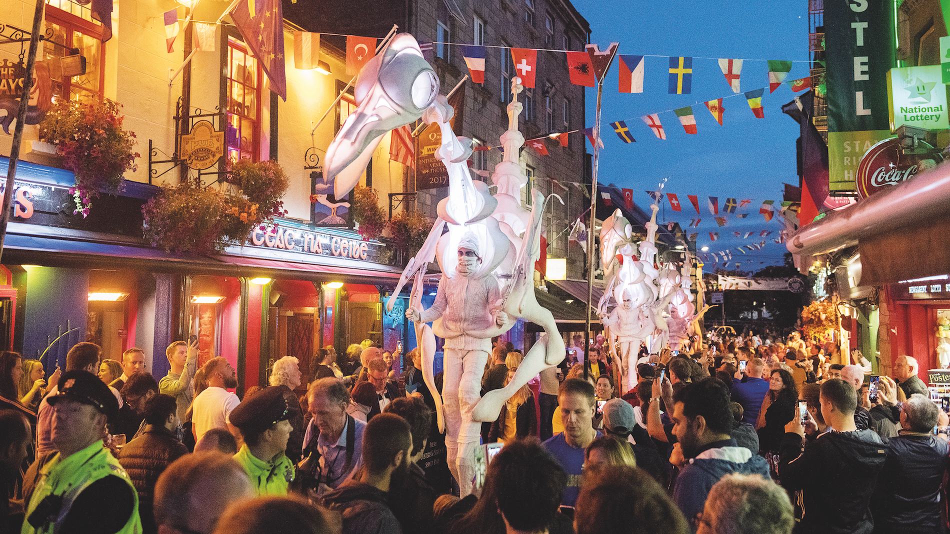 Crowds enjoy colourful street parade in Galway’s Latin Quarter during an evening festival.