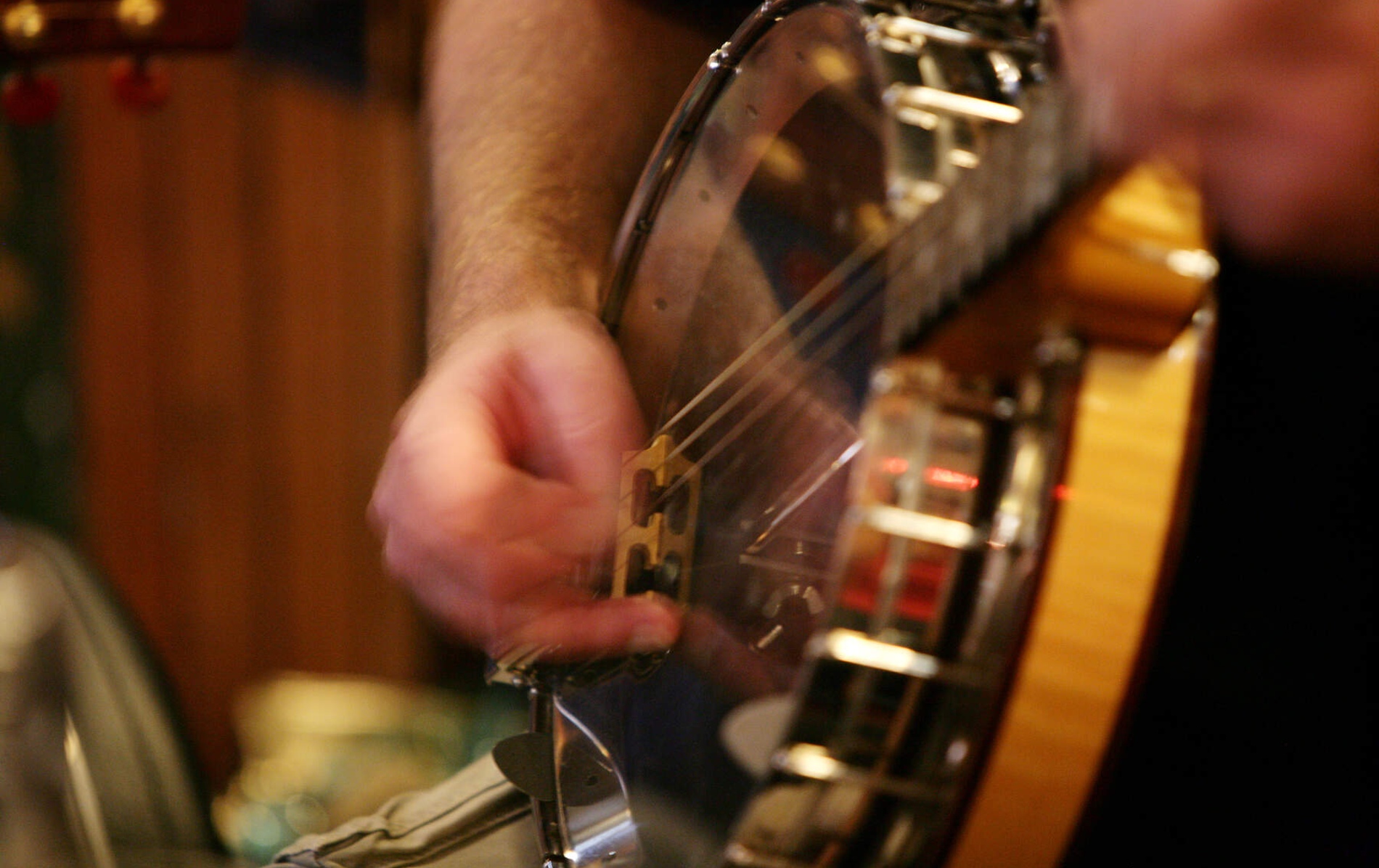 Close-up of a musician’s hand playing a banjo in a traditional music session.
