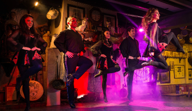 Energetic Irish dancers performing in a traditional setting with red and purple stage lighting at Johnnie Fox’s Pub in Dublin.