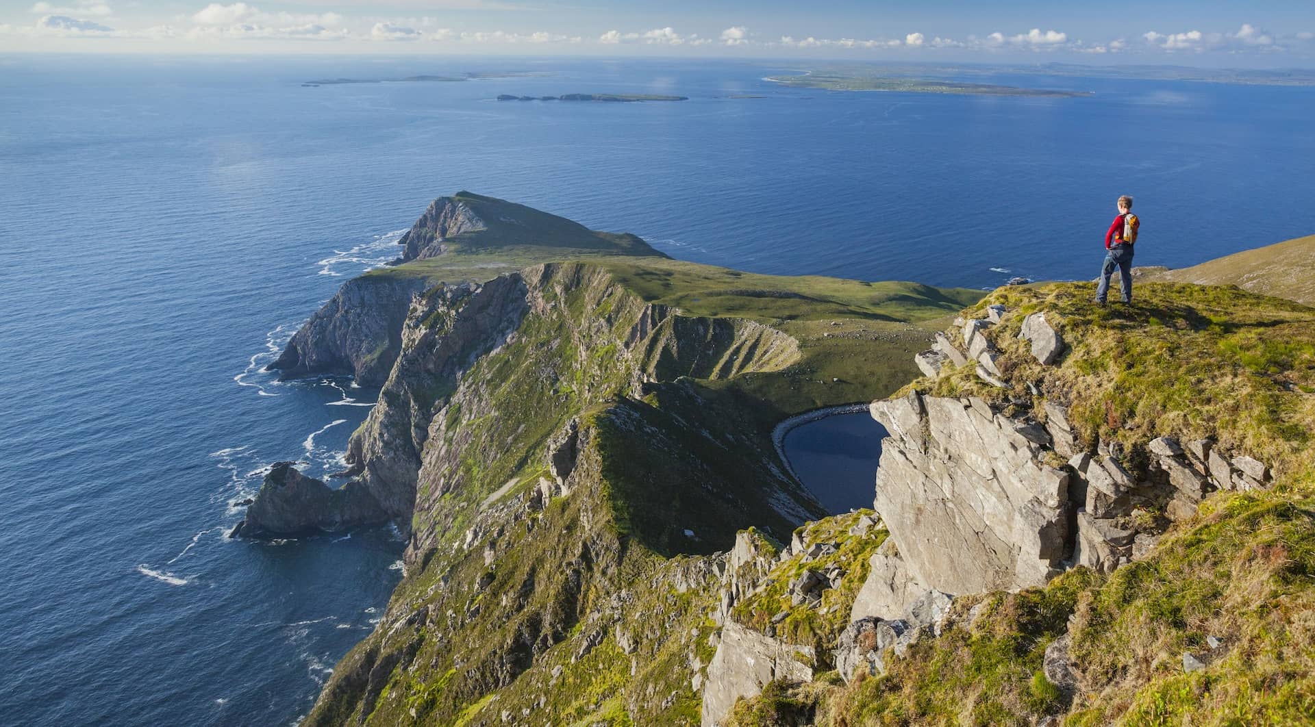 Hiker overlooking Croaghaun Cliffs and Atlantic Ocean on Achill Island, County Mayo, Ireland.