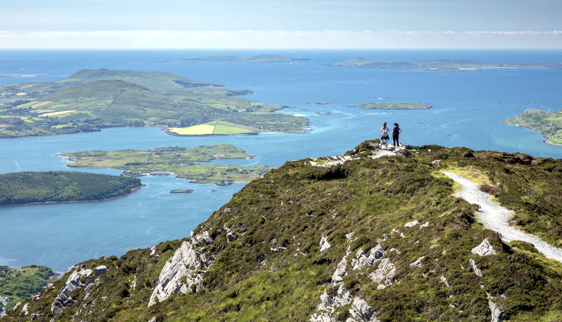 Hikers on Diamond Hill trail overlooking the Connemara coastline and islands in County Galway.