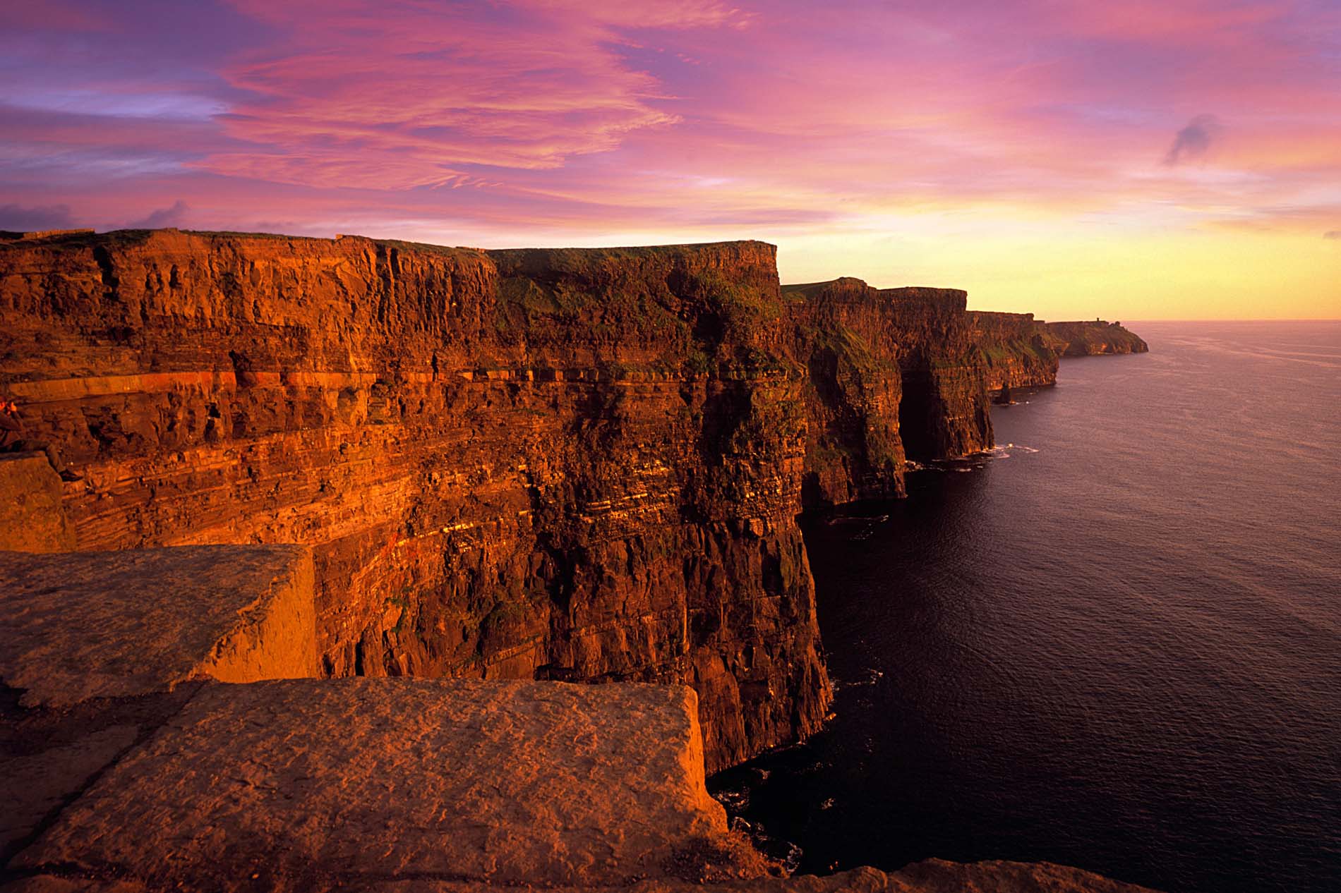 Cliffs of Moher glowing in the sunset light along the Wild Atlantic Way in County Clare, Ireland.