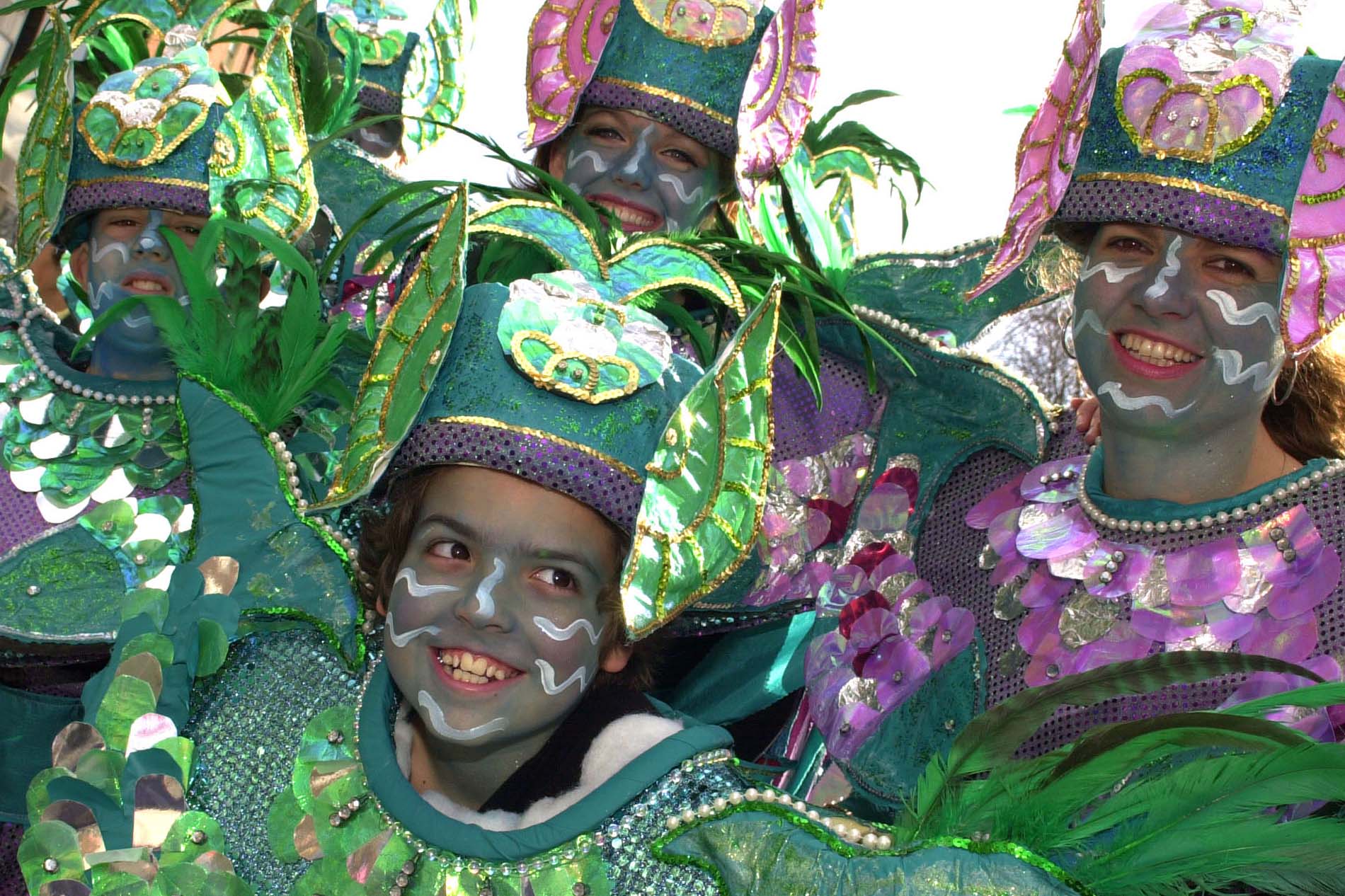 Smiling performers in colourful green and purple costumes at a St Patrick’s Day parade in Ireland.