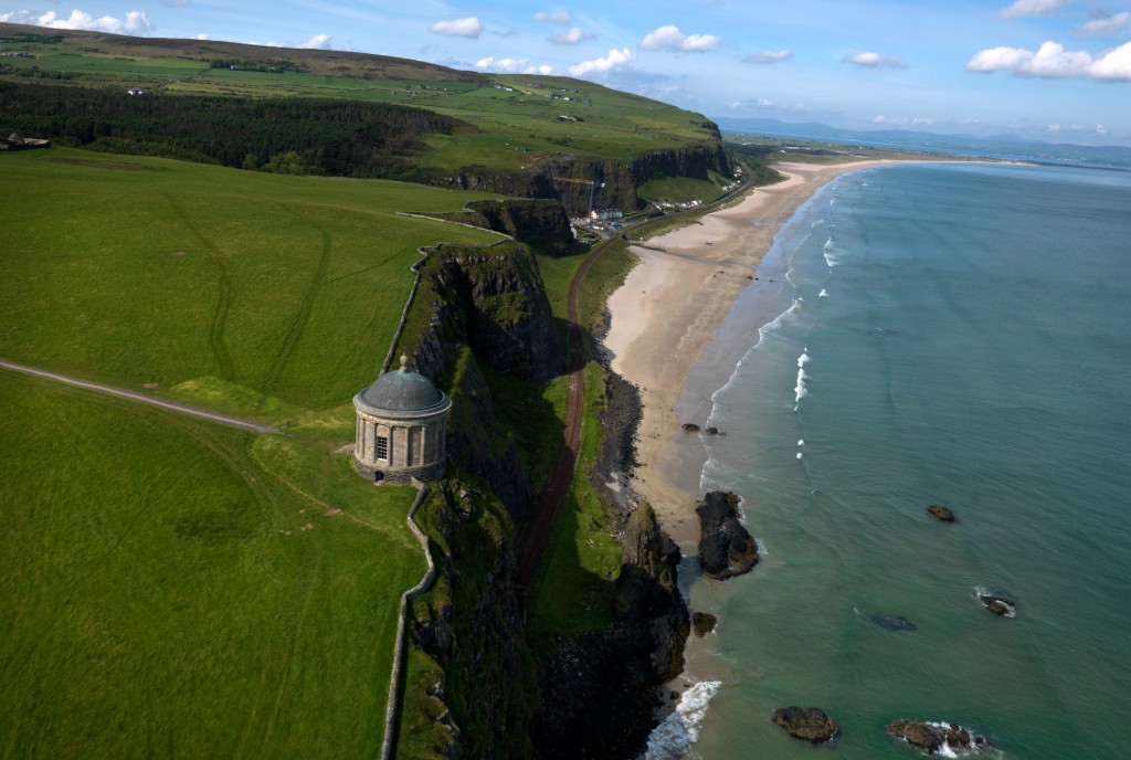 Mussenden Temple perched above Downhill Strand beach in County Londonderry with grassy cliffs and a long sandy shoreline.