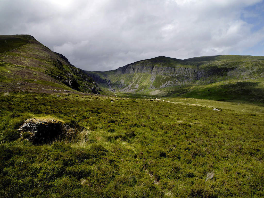 Rolling green slopes and rocky cliffs of the Comeragh Mountains in County Waterford.