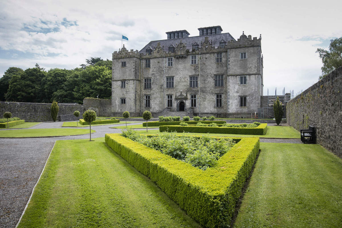 Formal hedged gardens leading to the grand façade of Portumna Castle, County Galway.