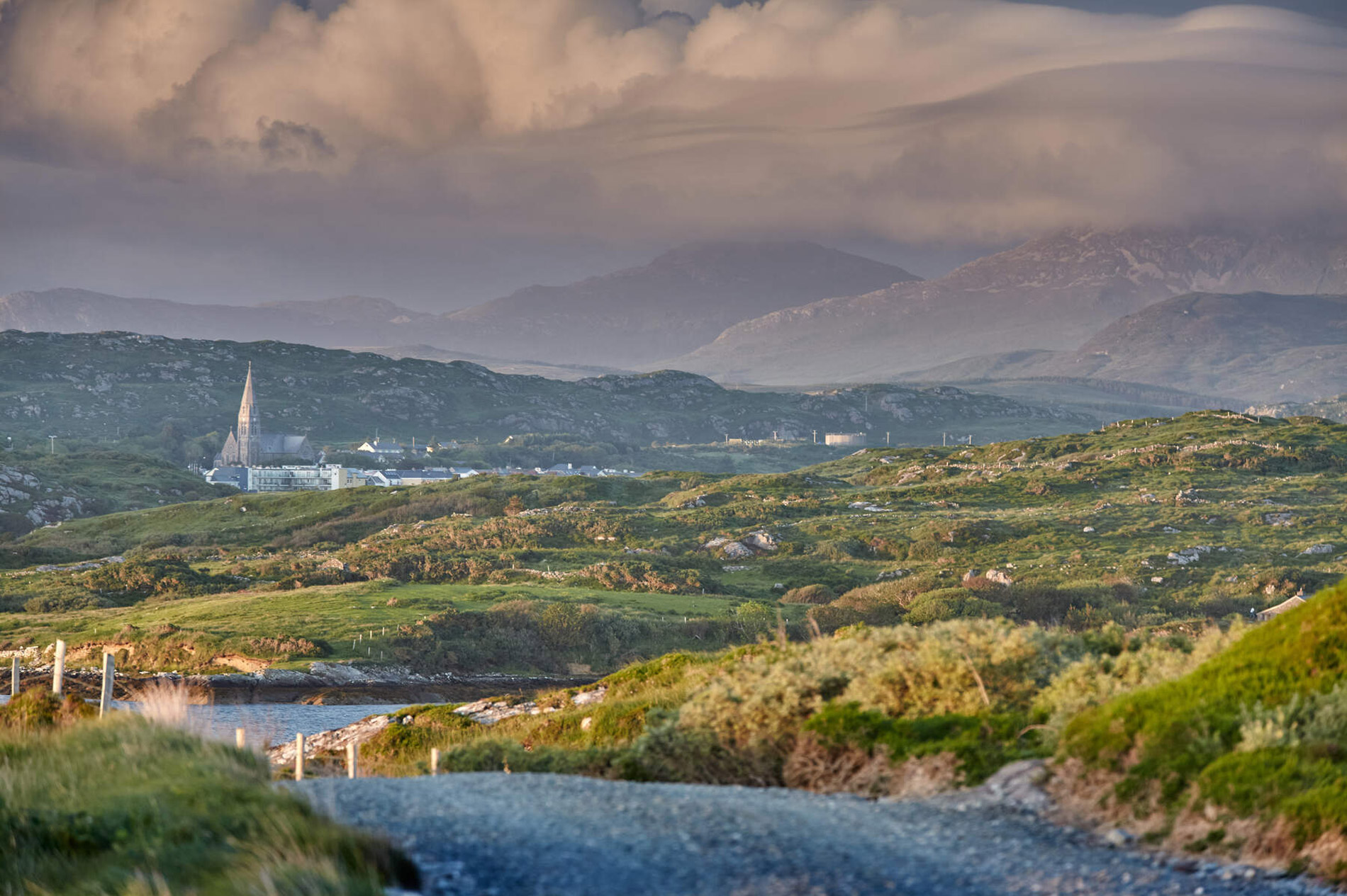 Peaceful rural village landscape with church spire and mountains, promoting B&B stays in the Irish countryside.